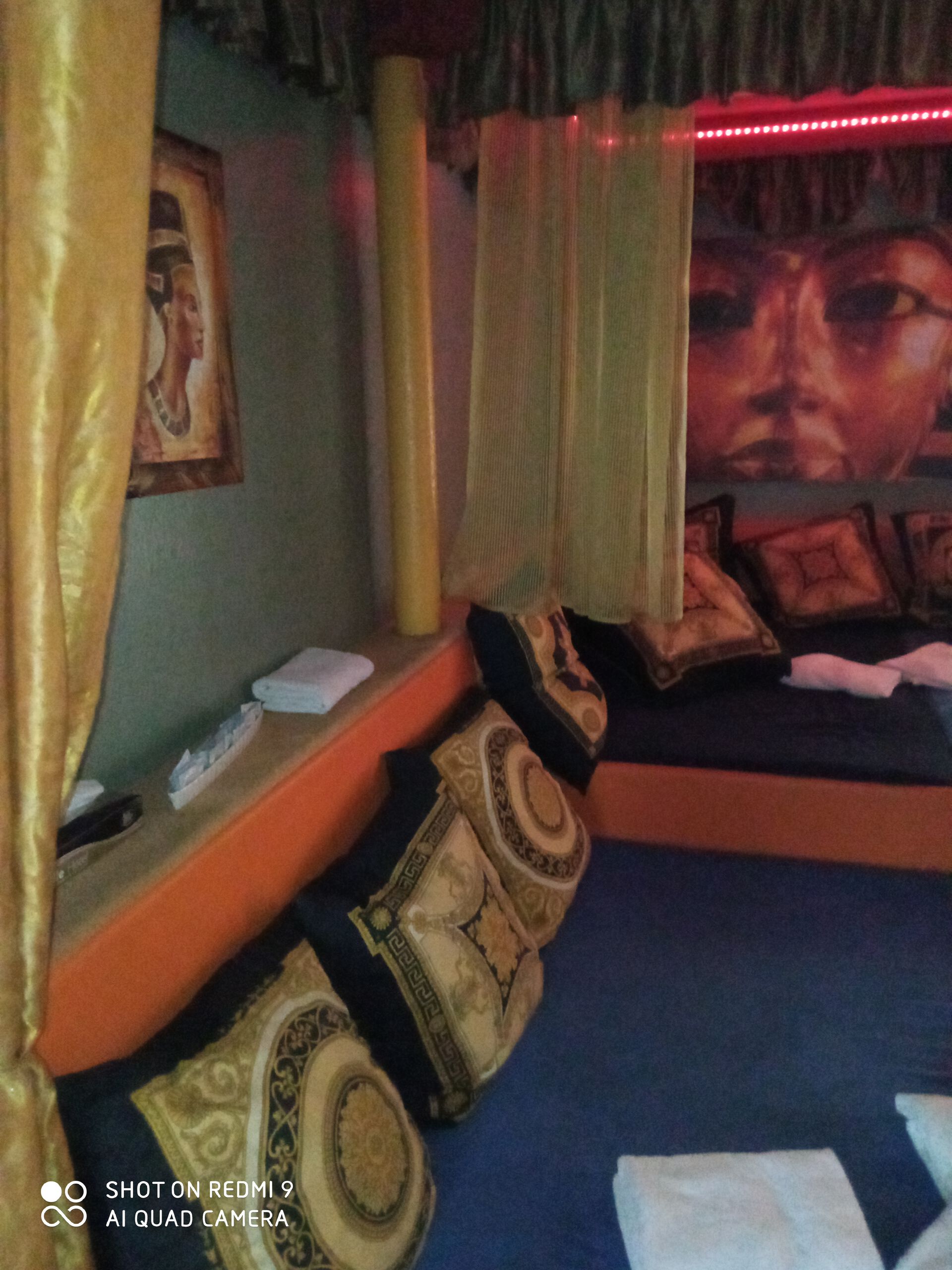 Ägypten-Zimmer mit goldenen Vorhängen, Kissen und Wandbildern.