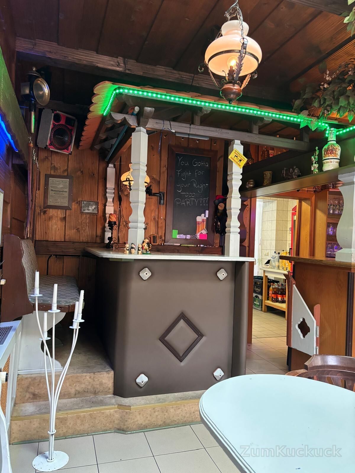 Holzterrasse an der Bar mit Theke, grüner Lichtleiste und Tafel.